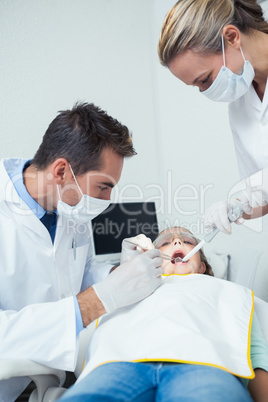 Male dentist  with assistant examining girls teeth