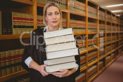 Lawyer holding heavy pile of books standing