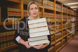 Lawyer holding heavy pile of books standing