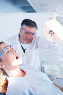 Dentist examining a patients teeth in chair under bright light