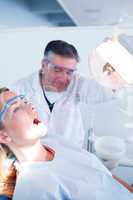 Dentist examining a patients teeth in chair under bright light