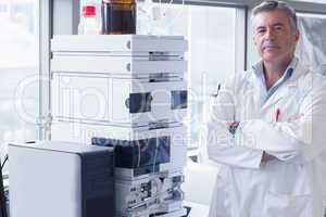 Scientist standing with arms crossed next to the machine