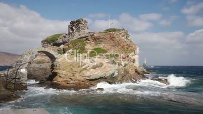 Rock and lighthouse at the stormy sea on greek island Andros