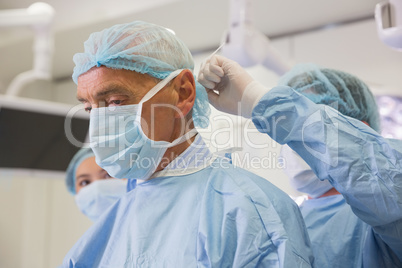 Medical student tying professors surgical mask