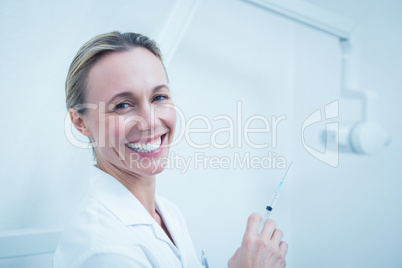 Smiling female dentist holding injection