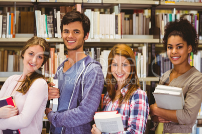 Students in a line smiling at camera holding books Students in a line smiling at camera holding books