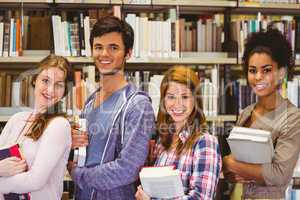 Students in a line smiling at camera holding books