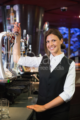 Happy barmaid pulling a pint of beer