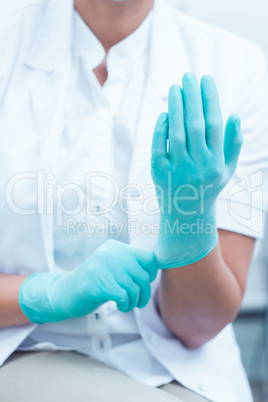 Mid section of dentist wearing surgical glove