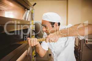 Baker taking bread out of oven