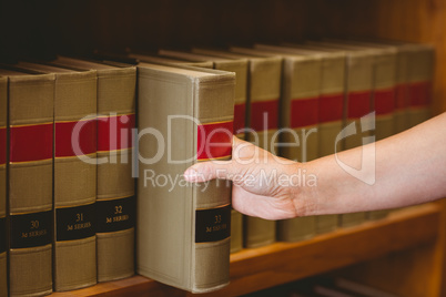 Hand taking a book from bookshelf