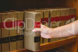 Hand taking a book from bookshelf