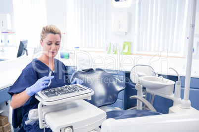 Smiling dentist sitting with tray of tools