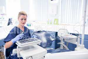 Smiling dentist sitting with tray of tools