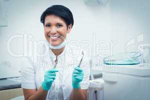 Happy female dentist holding dental tools