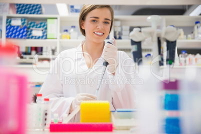 Pretty science student using pipette