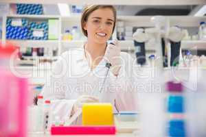 Pretty science student using pipette