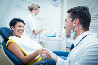 Male dentist shaking hands with woman