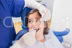 Pediatric dentist doing examination at a scared young patient