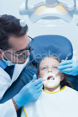 Male dentist examining girls teeth