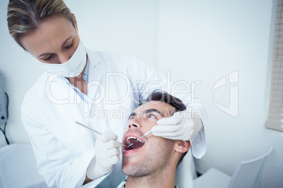 Female dentist examining mans teeth