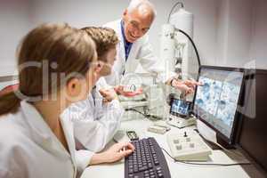 Science students looking at microscopic image on computer with l