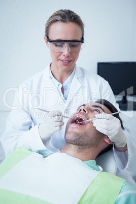 Female dentist examining mans teeth