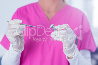 Dentist in pink scrubs holding tool