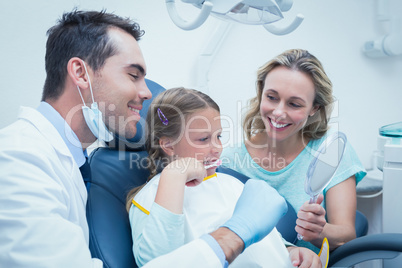 Dentist examining girls teeth with assistant