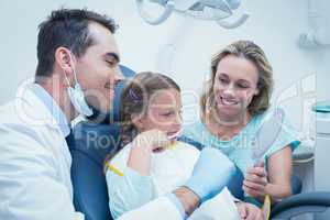 Dentist examining girls teeth with assistant