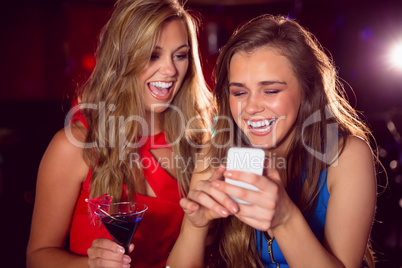 Pretty friends looking at smartphone together