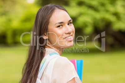Portrait of a smiling student with a shoulder bag and holding bo