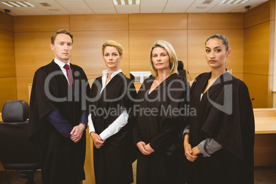 Four serious judges standing while wearing robes