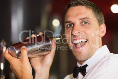 Handsome barman smiling at camera making a cocktail