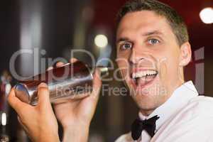 Handsome barman smiling at camera making a cocktail