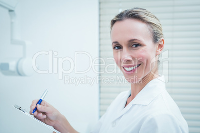 Smiling female dentist holding clipboard