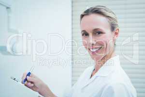 Smiling female dentist holding clipboard