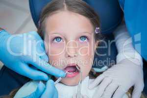 Dentist with assistant examining girls teeth