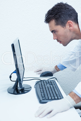 Concentrated male dentist looking at computer monitor