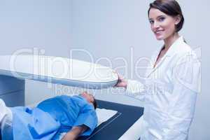 Smiling doctor with a patient under x-ray machine