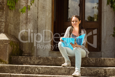 Smiling student sitting and holding book