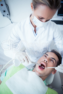 Female dentist examining mans teeth