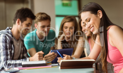 Smiling friends sitting studying and using tablet pc