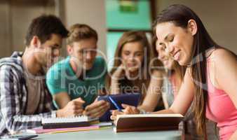 Smiling friends sitting studying and using tablet pc