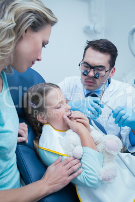 Dentist examining girls teeth with assistant