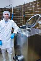 Smiling biologist leaning against storage tank