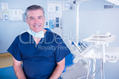 Dentist smiling at camera beside chair