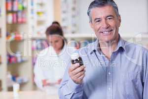 Smiling man with a bottle of pills
