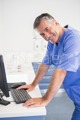 Portrait of a smiling dentist using computer