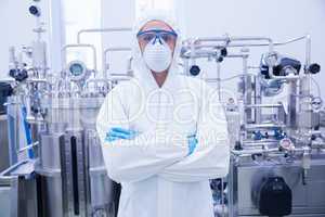 Scientist in protective suit standing with arms crossed